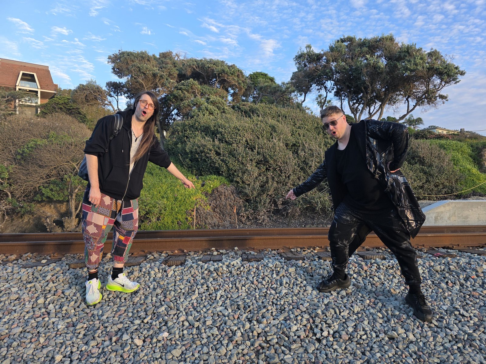 Goose and Squirrelybass pointing at railroad tracks by the coast, mock-alarmed